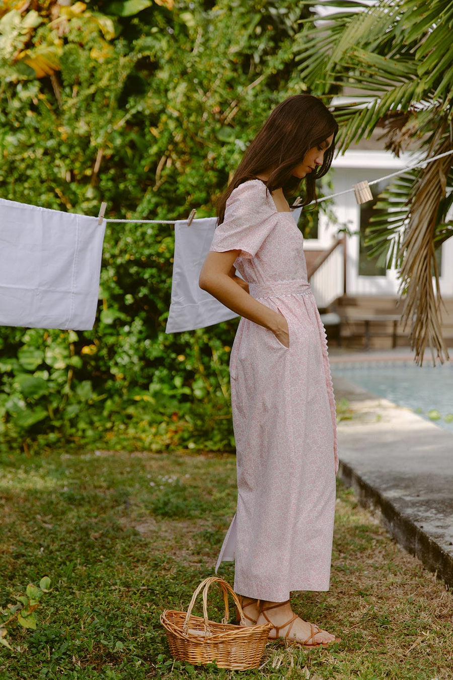 Woman wearing pink sundress by a laundry line